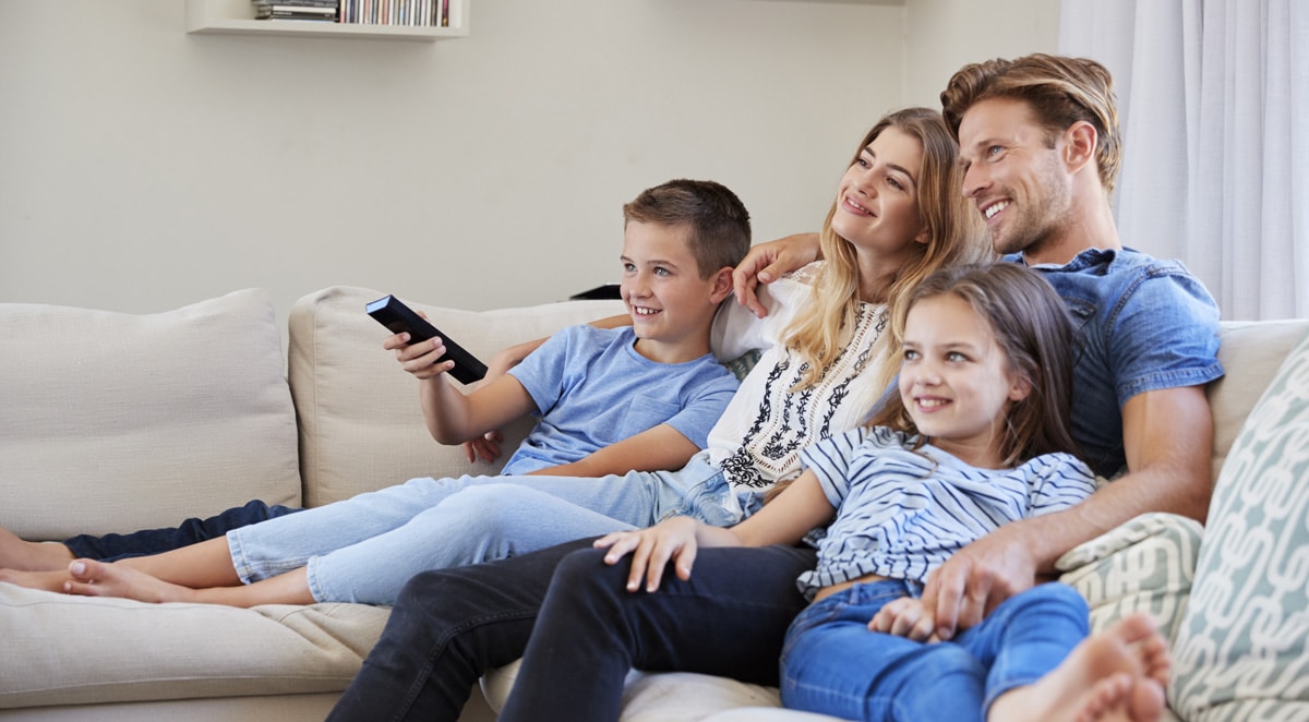 A family of four watching television together in a modern living room