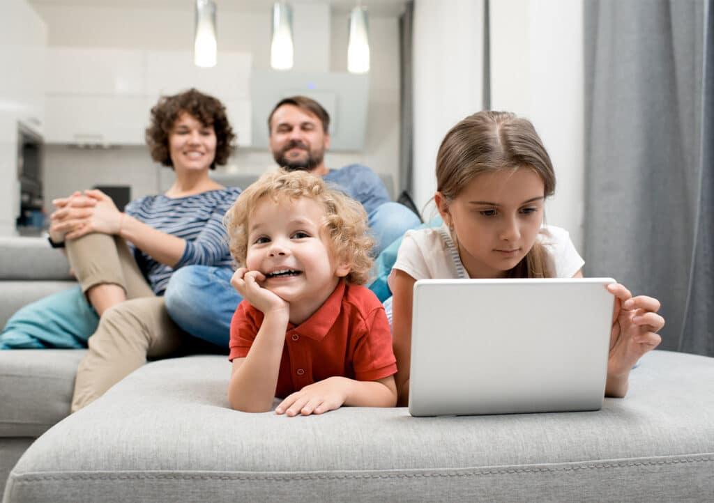 A mom, dad, son, and daughter spending time together watching TV in a living room.