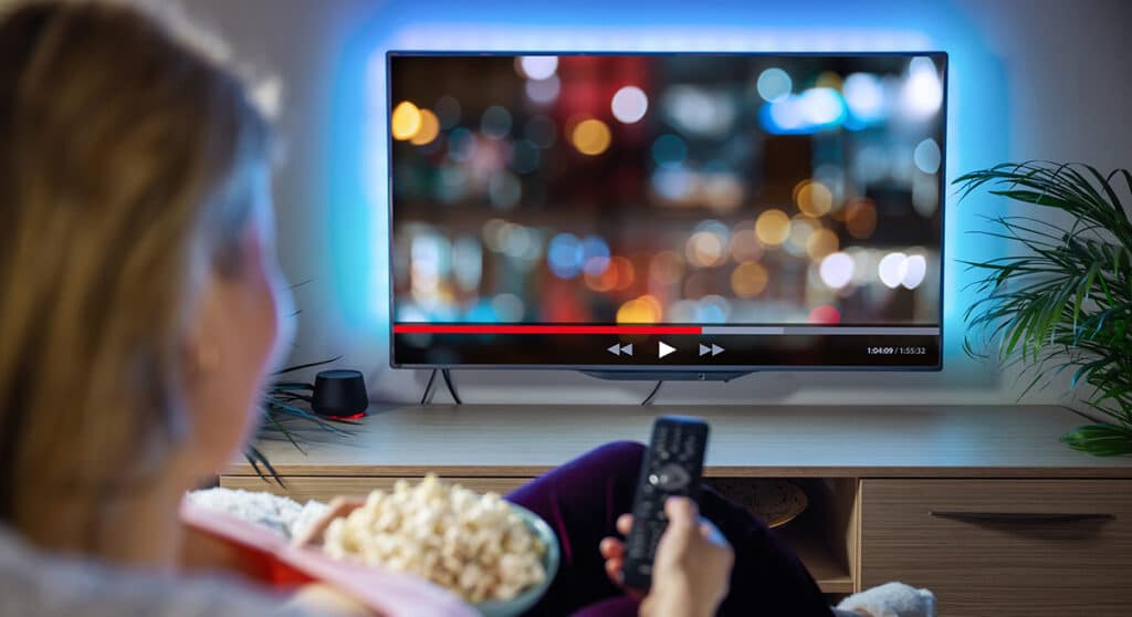 Person watching tv while holding remote and popcorn