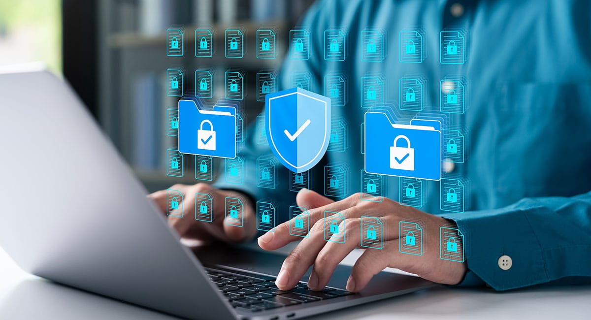 Person typing on laptop with security icons overlayed.